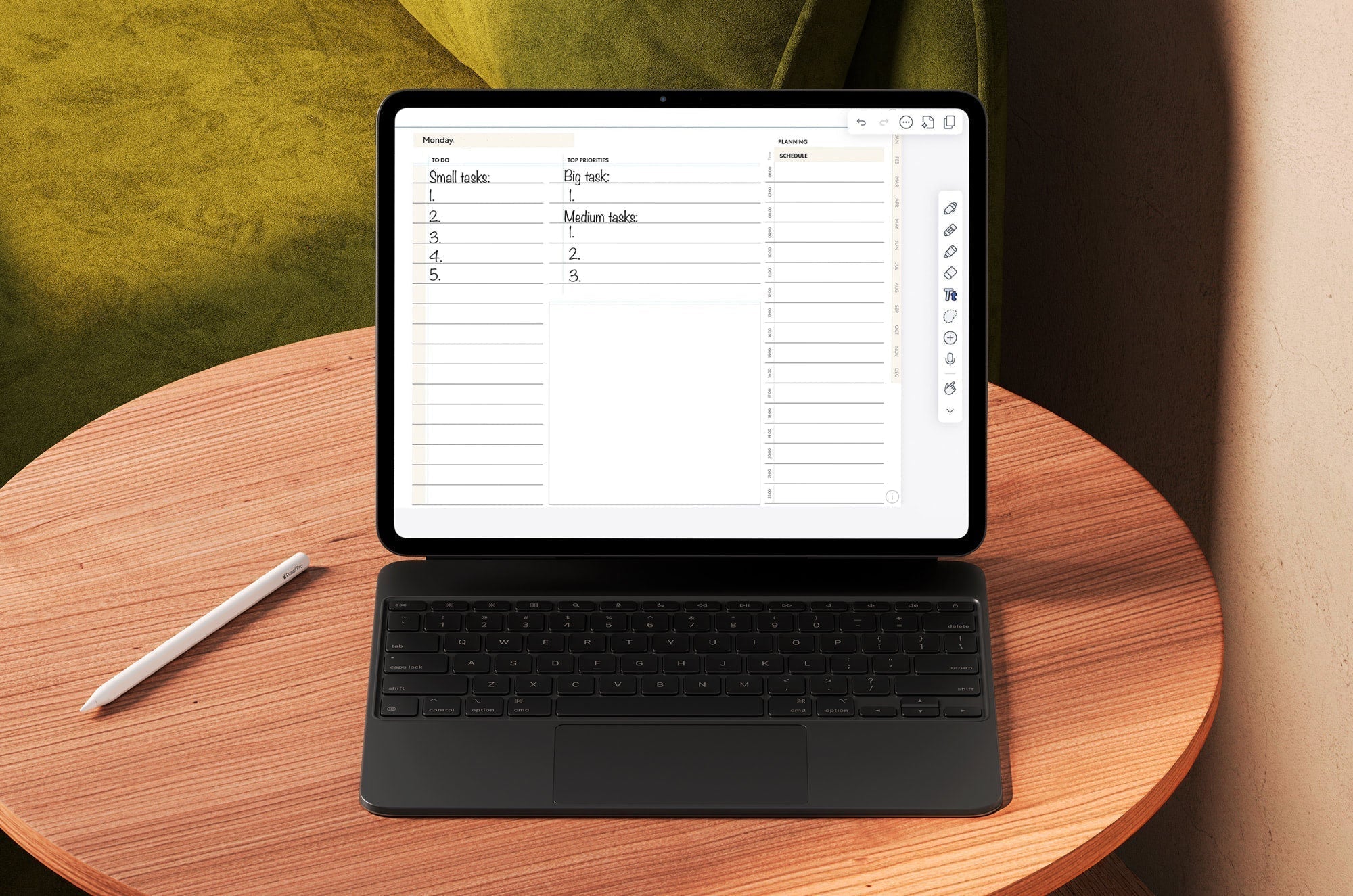 An iPad with a digital planner on the screen and a keyboard propped up on a small, wooden table with an Apple Pencil sitting next to it.