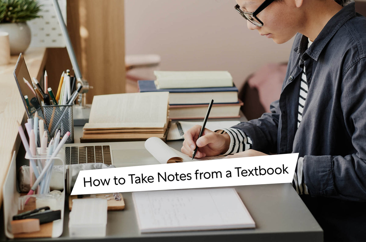 How to Take Notes from a Textbook. A woman sitting at a desk writing on her iPad. Containers with pencils and desk accessories sit in front of her as well as a macbook.