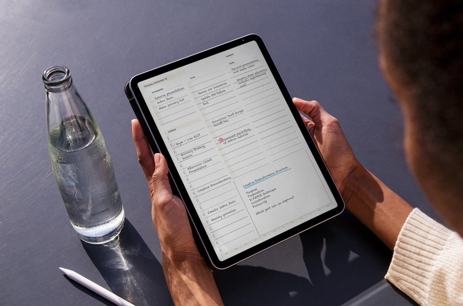 A person holding an iPad with a digital planner on the screen.