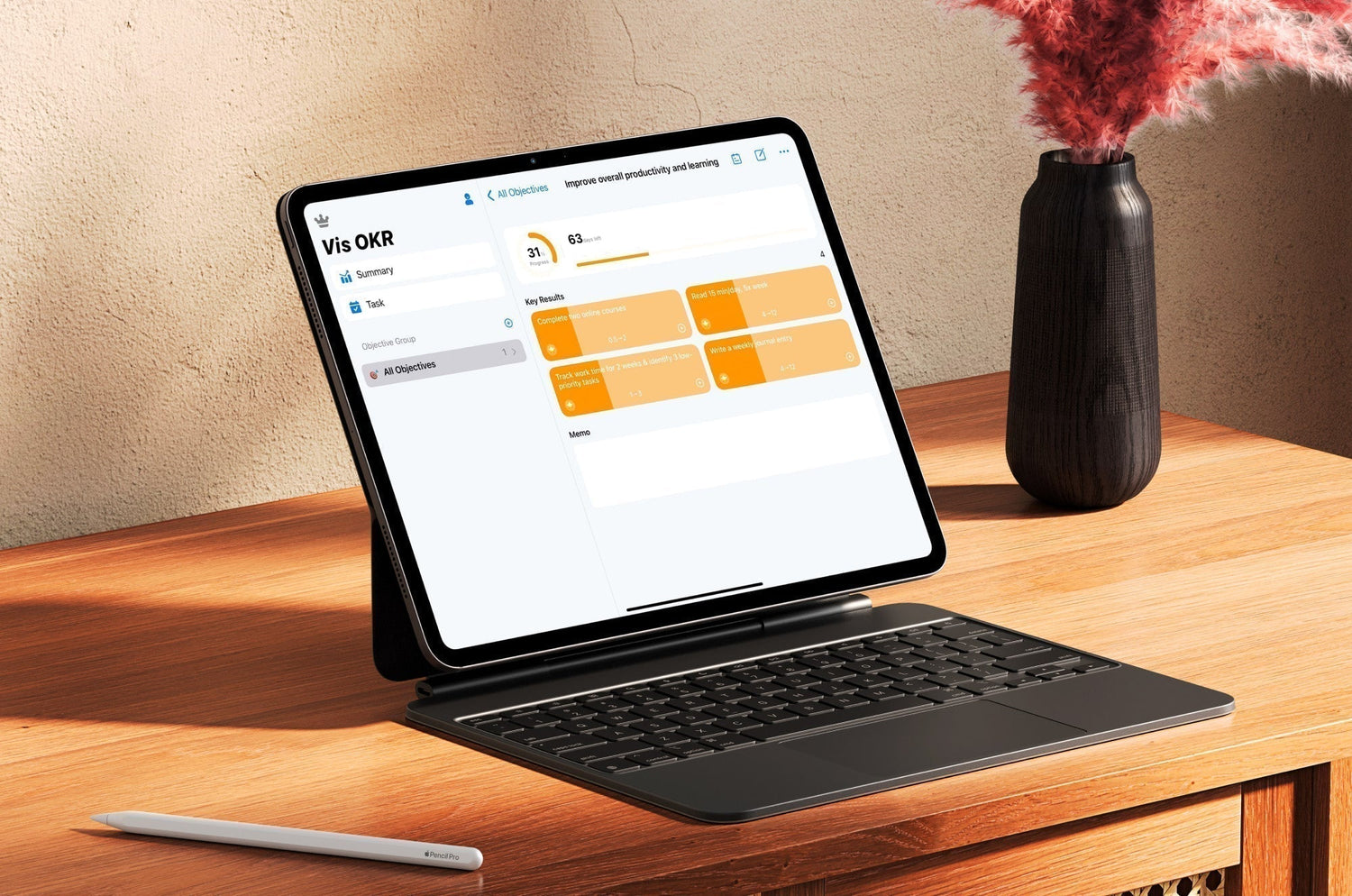 iPad on a keyboard stand displaying Vis OKR productivity app with goals and progress tracking, placed on a wooden desk with a stylus and a vase of red dried flowers.