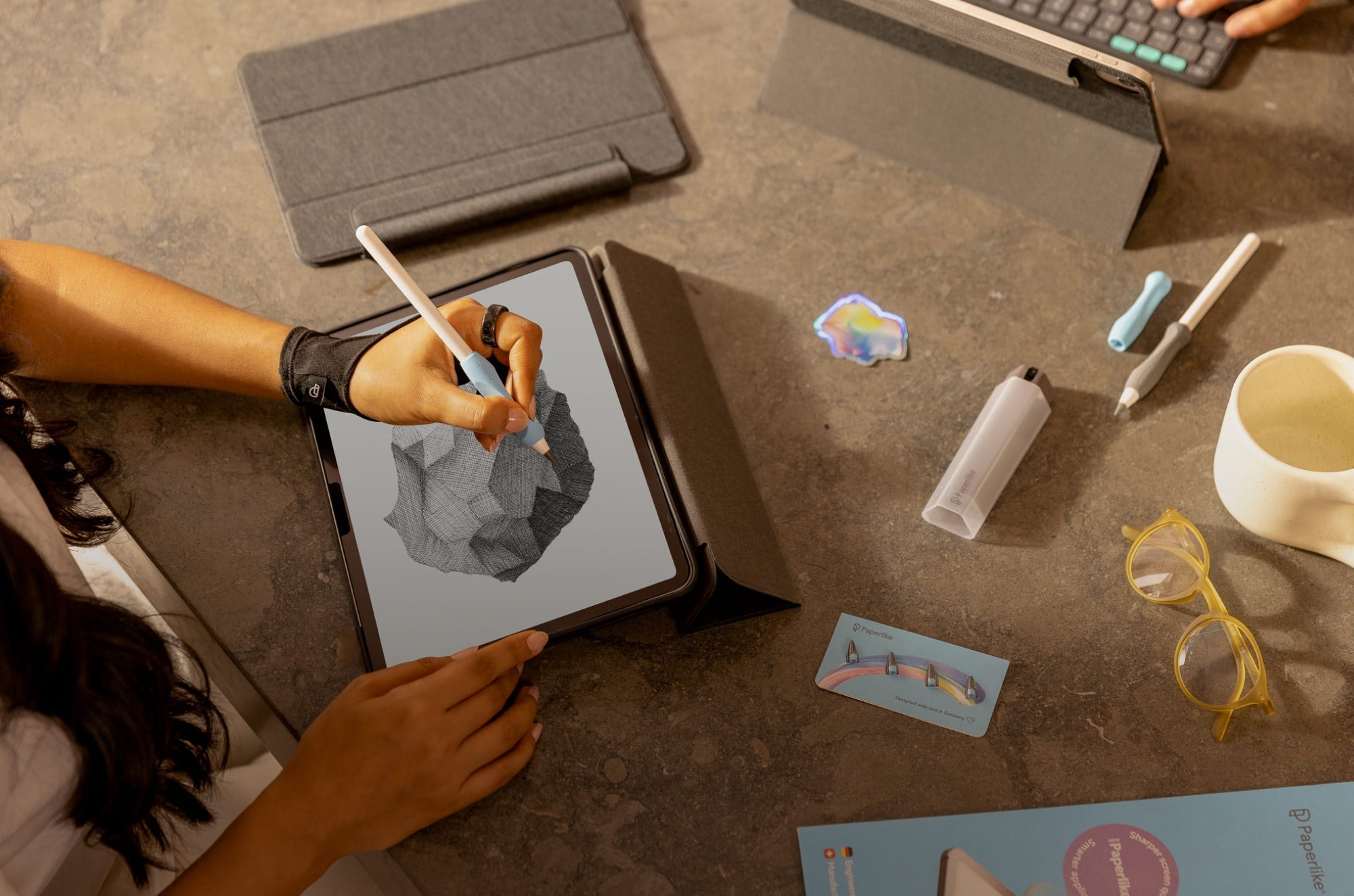 Someone writing on an iPad with an Apple Pencil surrounded by a bunch of Paperlike accessories.