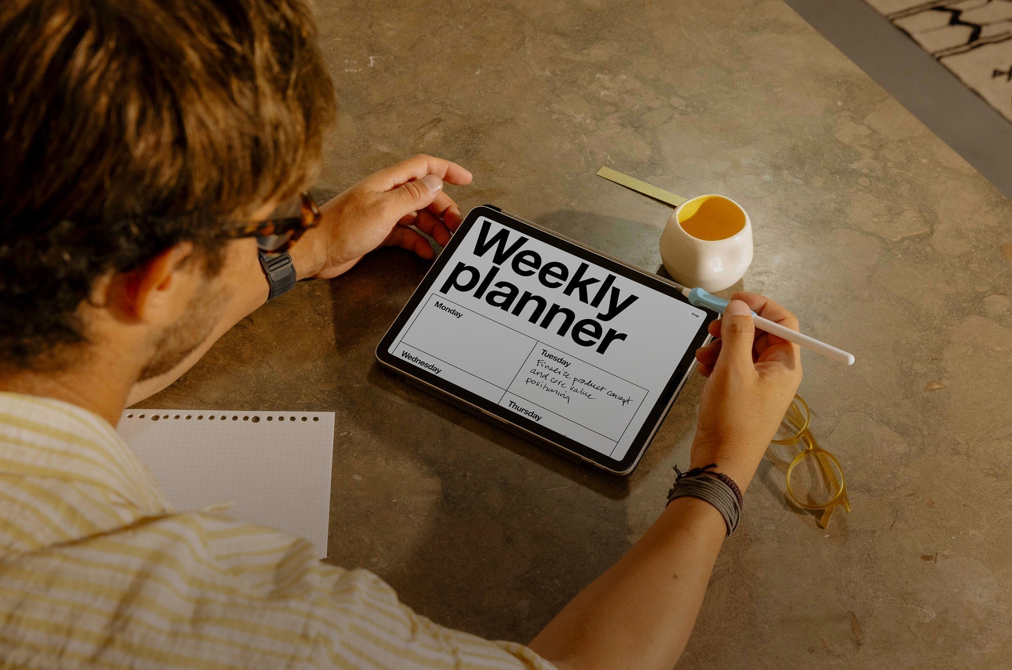 A man looking at an iPad with a weekly planner open on it.