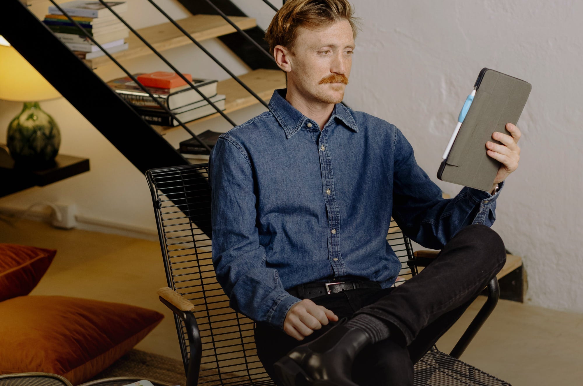 A man sitting in a chair and looking at an iPad.