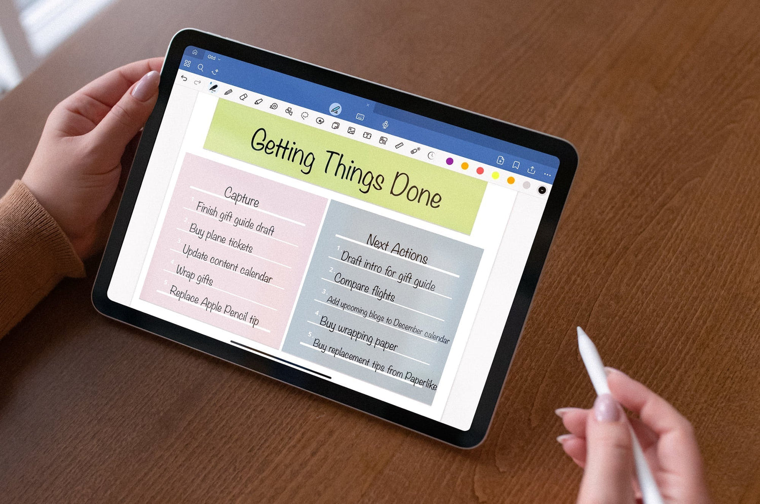 Person holding an iPad with a digital “Getting Things Done” planner open, handwritten task lists visible, and an Apple Pencil in the other hand.