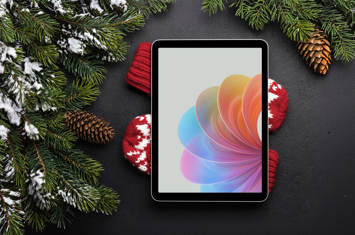 An iPad with a colorful design on the screen lying on top of red mittens with pine boughs around it.