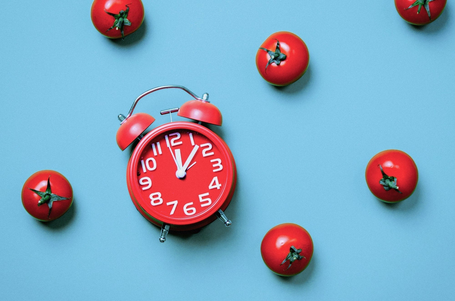 Pomodoro Technique time management concept with alarm clock and tomatoes.