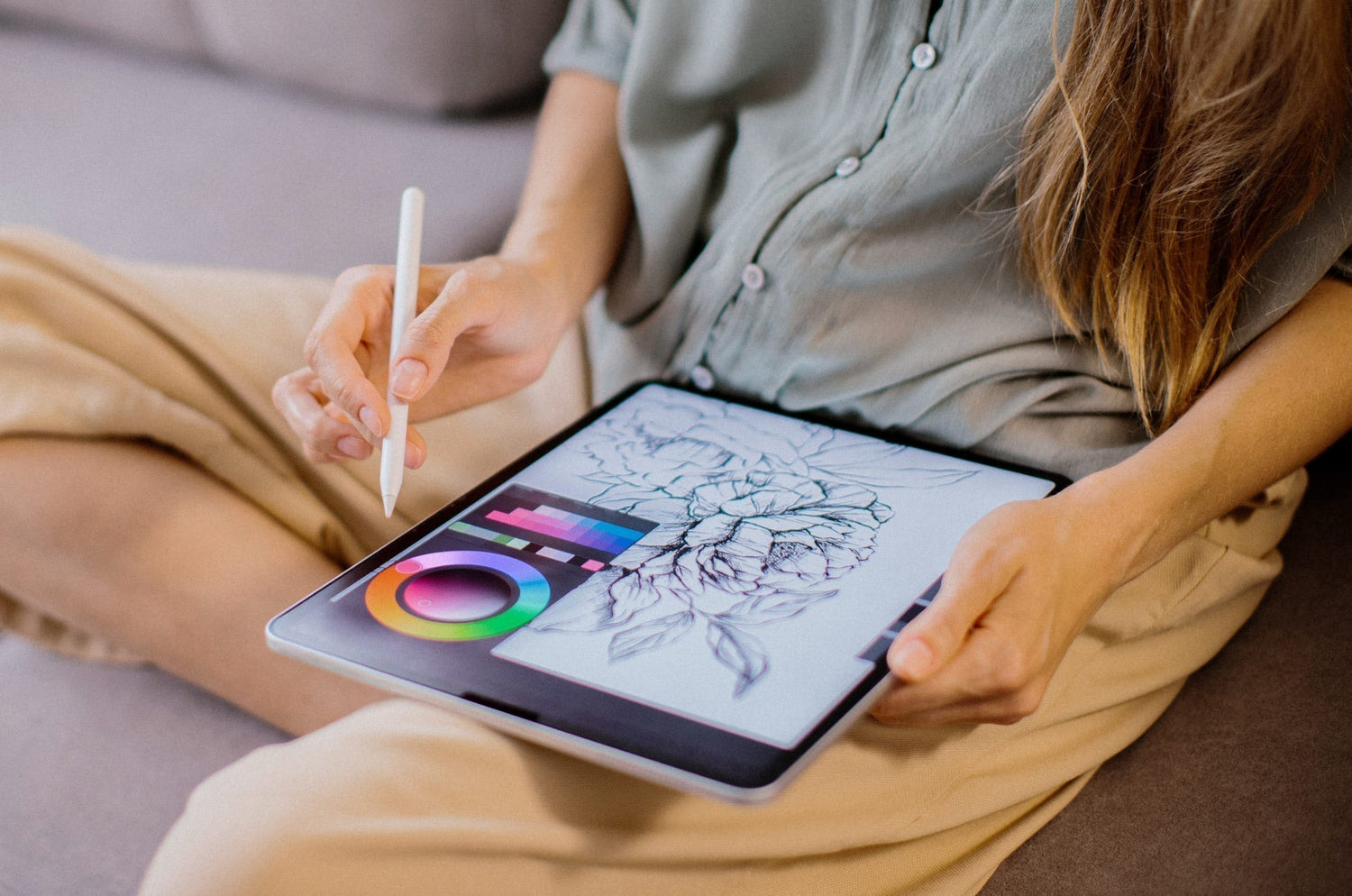 Woman drawing floral illustration on iPad with Apple Pencil.