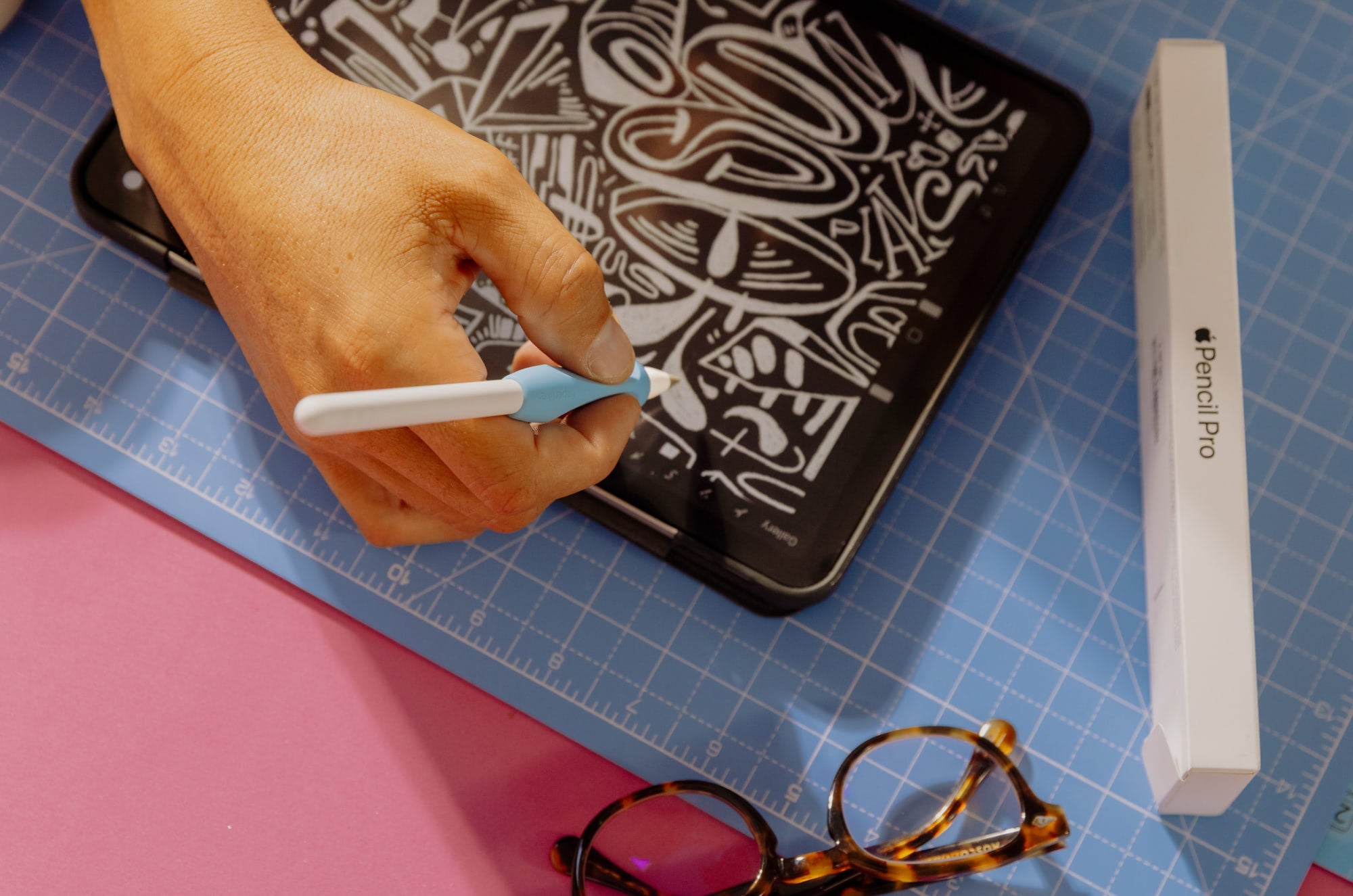 An overhead view of a hand writing on an iPad with an Apple Pencil
