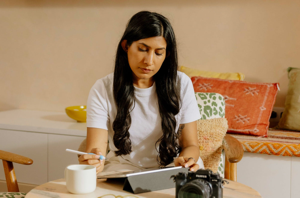 A woman holding an Apple Pencil and looking down at an iPad.