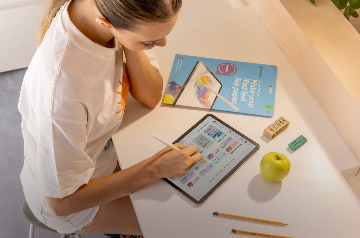A girl writing on an iPad with an Apple Pencil with a Paperlike Screen Protector package sitting next to it.