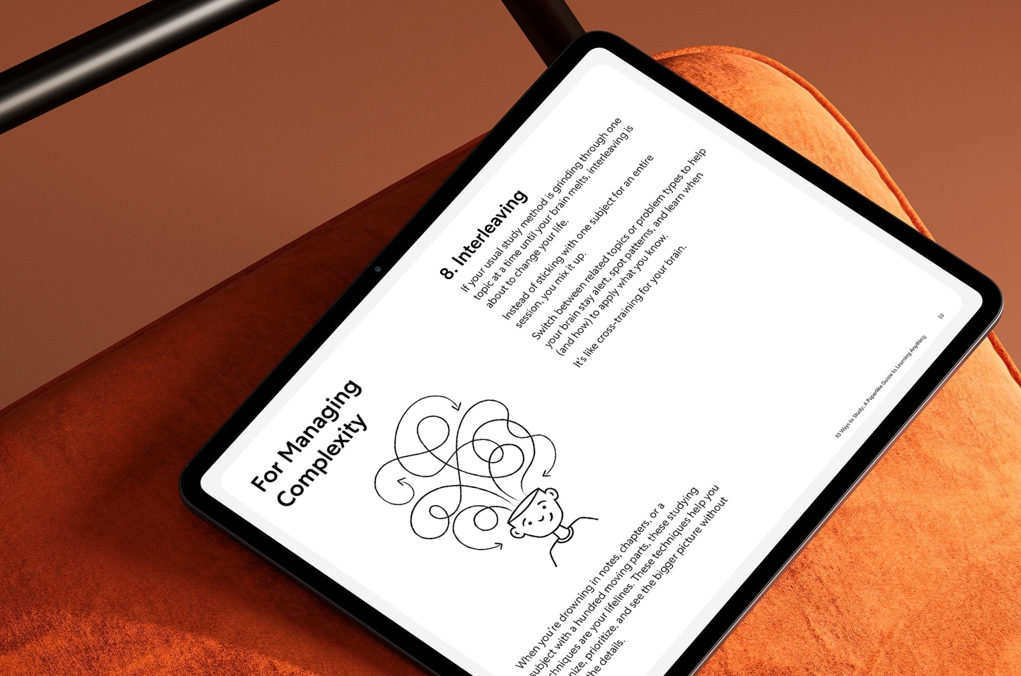 An iPad with a image and description of interleaving on it, lying on an orange chair cushion.