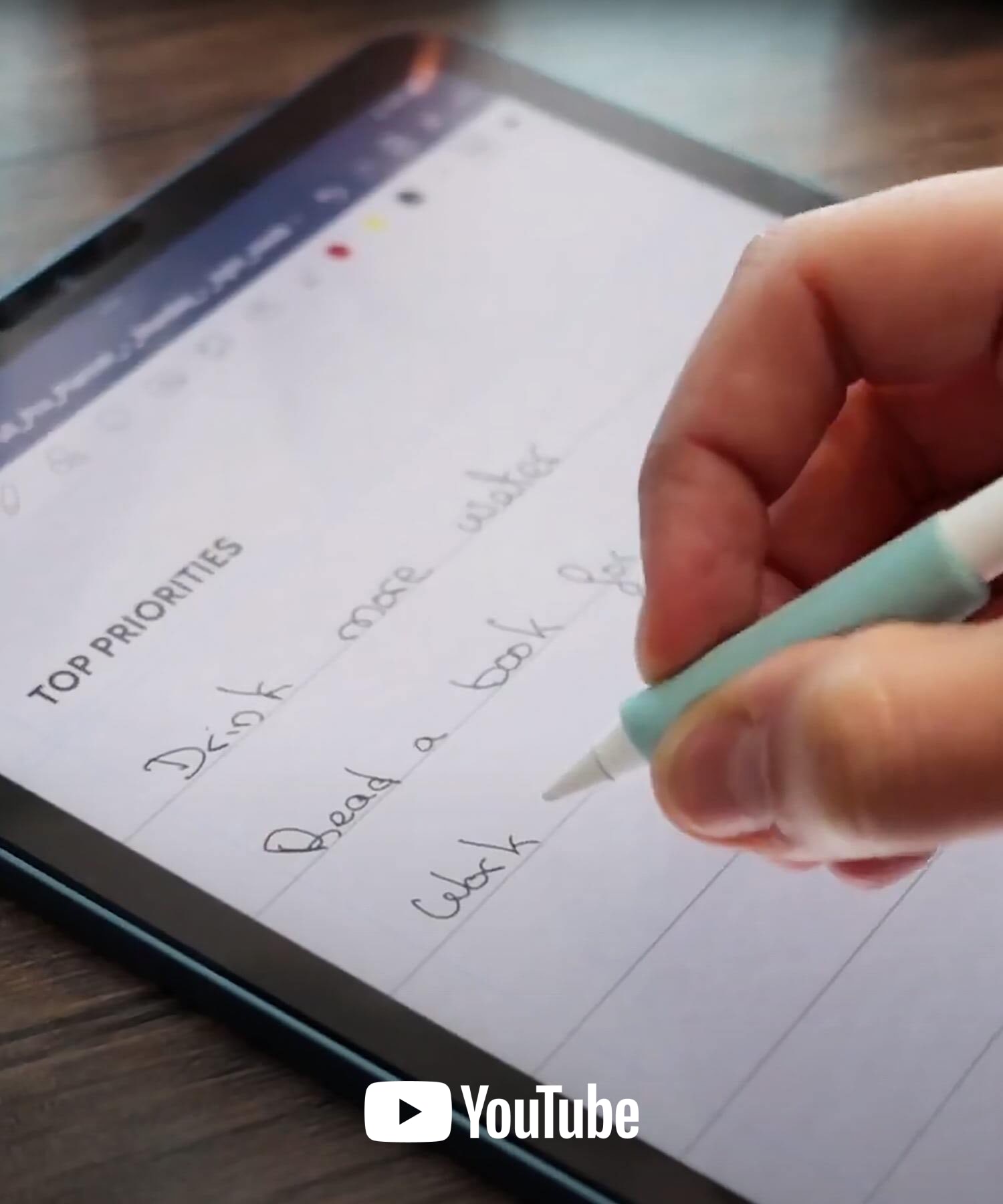 A close-up of a hand holding an Apple Pencil with a mint green pencil grip writing a list of top priorities with the YouTube logo at the bottom.