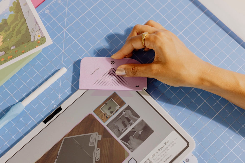 Person aligning the screen protector with the help of the Helper Tool.