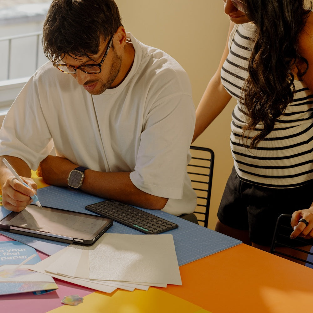 Person working on an iPad while another person looks over their shoulder.